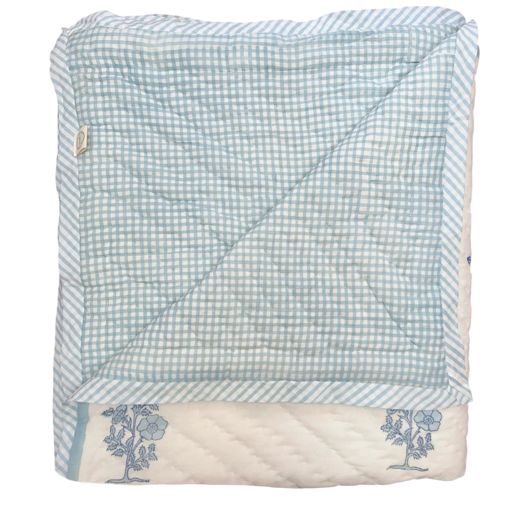 Folded hand block printed quilt with blue and white checkered pattern on a white background The Charpoy
