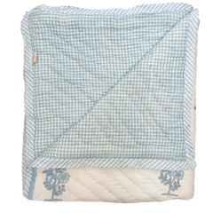 Folded hand block printed quilt with blue and white checkered pattern on a white background The Charpoy