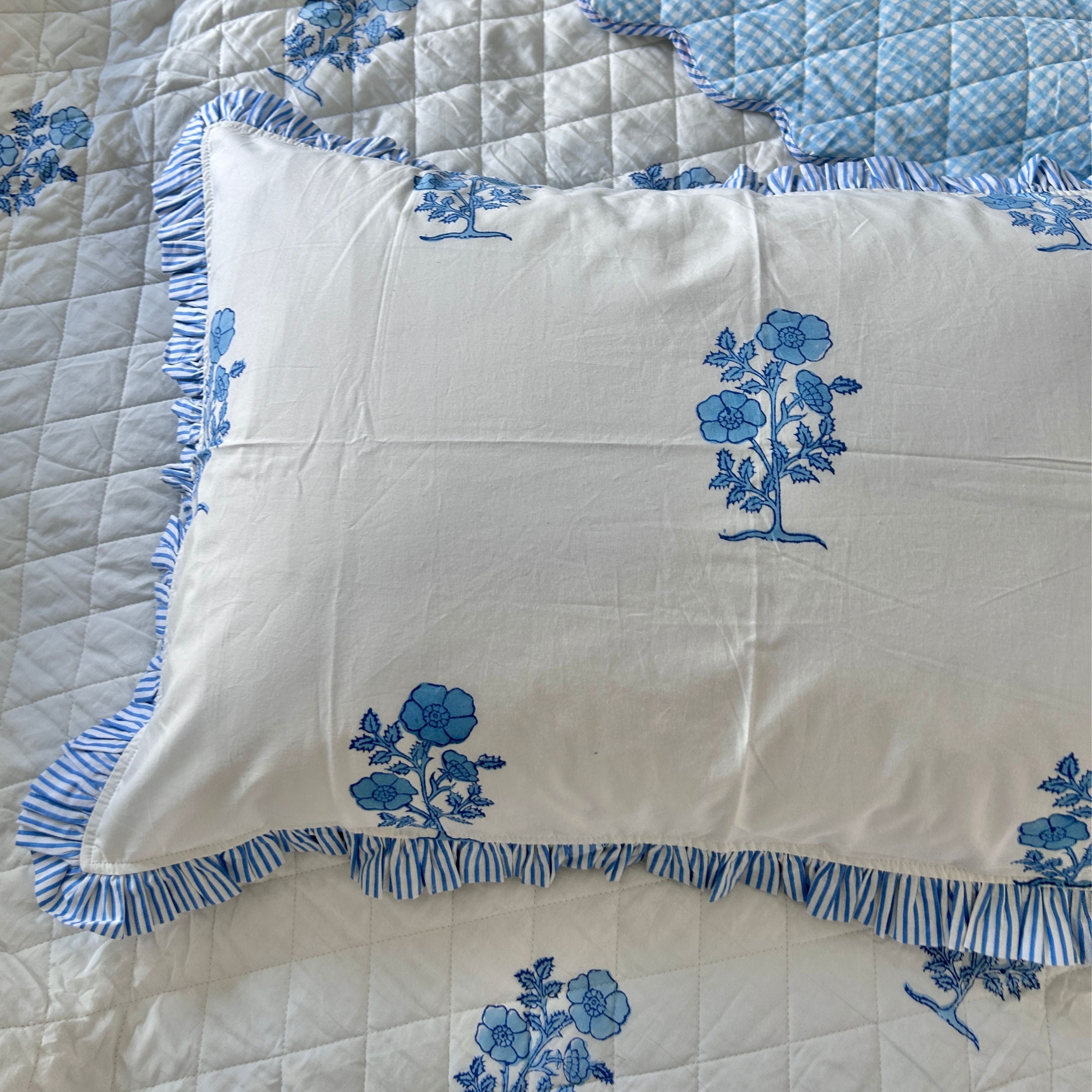 White pillow with blue floral hand block printing on a matching bedspread. the Charpoy