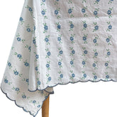 Close up of the blue petit daisy block printed motifs and embroidered scalloped border on a white cotton tablecloth by The Charpoy