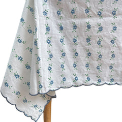 Close up of the blue petit daisy block printed motifs and embroidered scalloped border on a white cotton tablecloth by The Charpoy