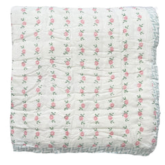 A hand block printed cotton quilt with a floral motif in pink and green, featuring a solid white background. The Charpoy