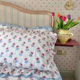 Floral hand block printed pillow covers with a vase of tulips on a shelf in a bedroom. The Charpoy