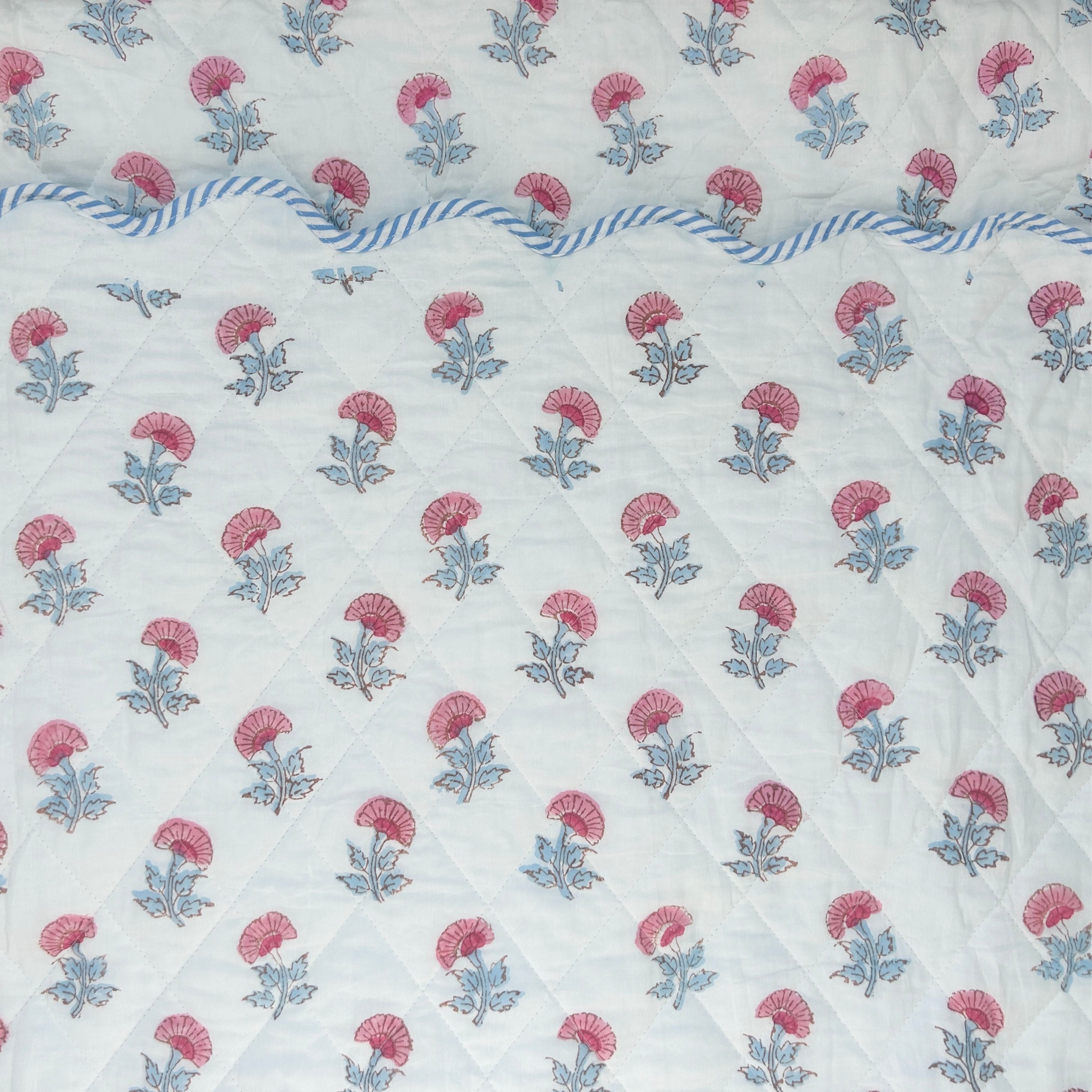 Floral patterned fabric scalopped bedpread with pink and blue flowers on a white background The Charpoy
