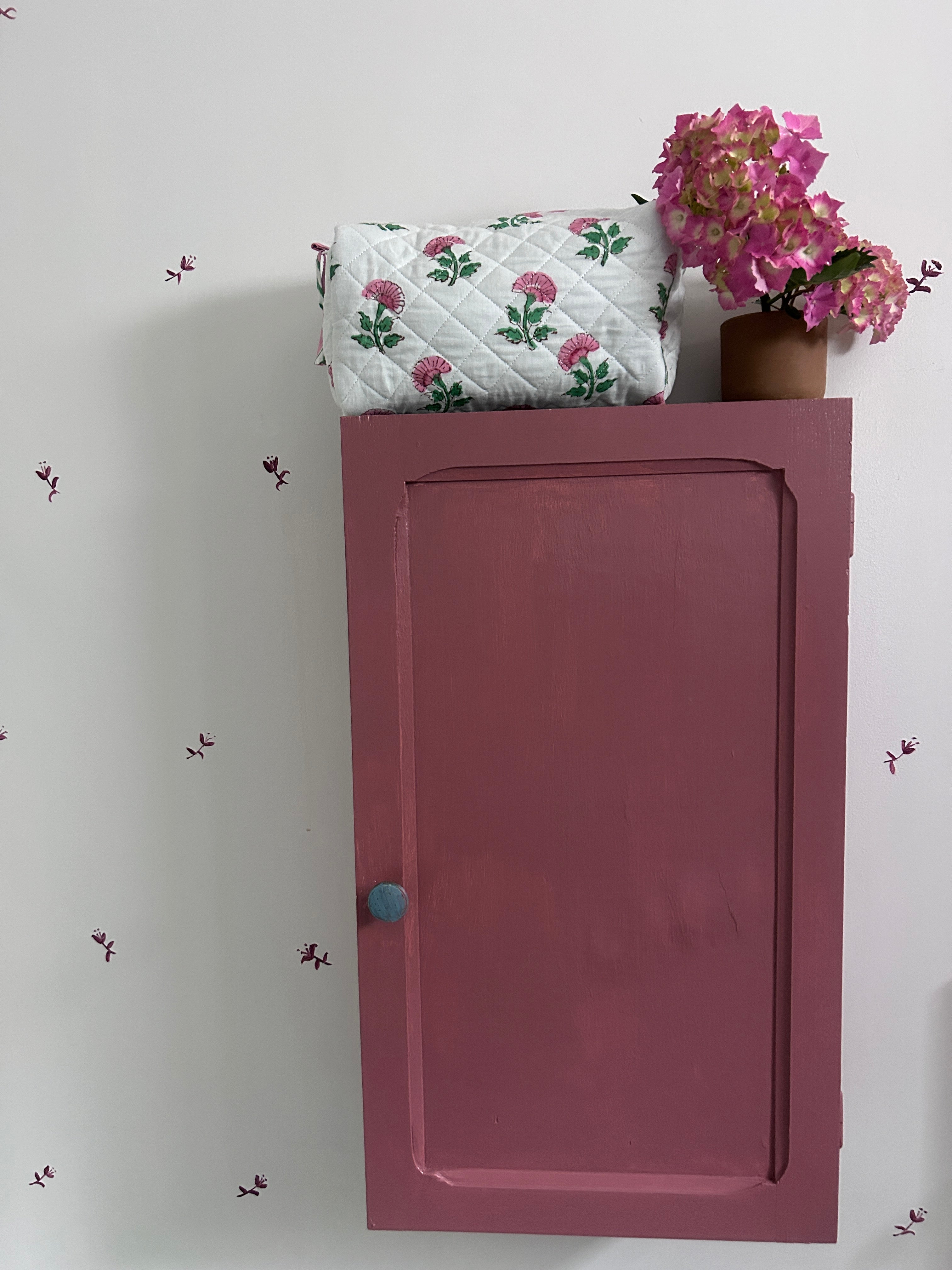 Pink And Green Flower Quilted Wash Bag hand block printed and lightly quilted by artisans in Jaipur by The Charpoy on a Pink cabinet and floral wall.