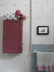 Pink And Green Flower Quilted Wash Bag hand block printed and lightly quilted by artisans in Jaipur by The Charpoy on a Pink cabinet and floral wall in a bathroom setting.