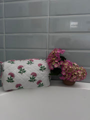 Pink And Green Flower Quilted Wash Bag hand block printed and lightly quilted by artisans in Jaipur by The Charpoy on a bath tub in a bathroom setting.