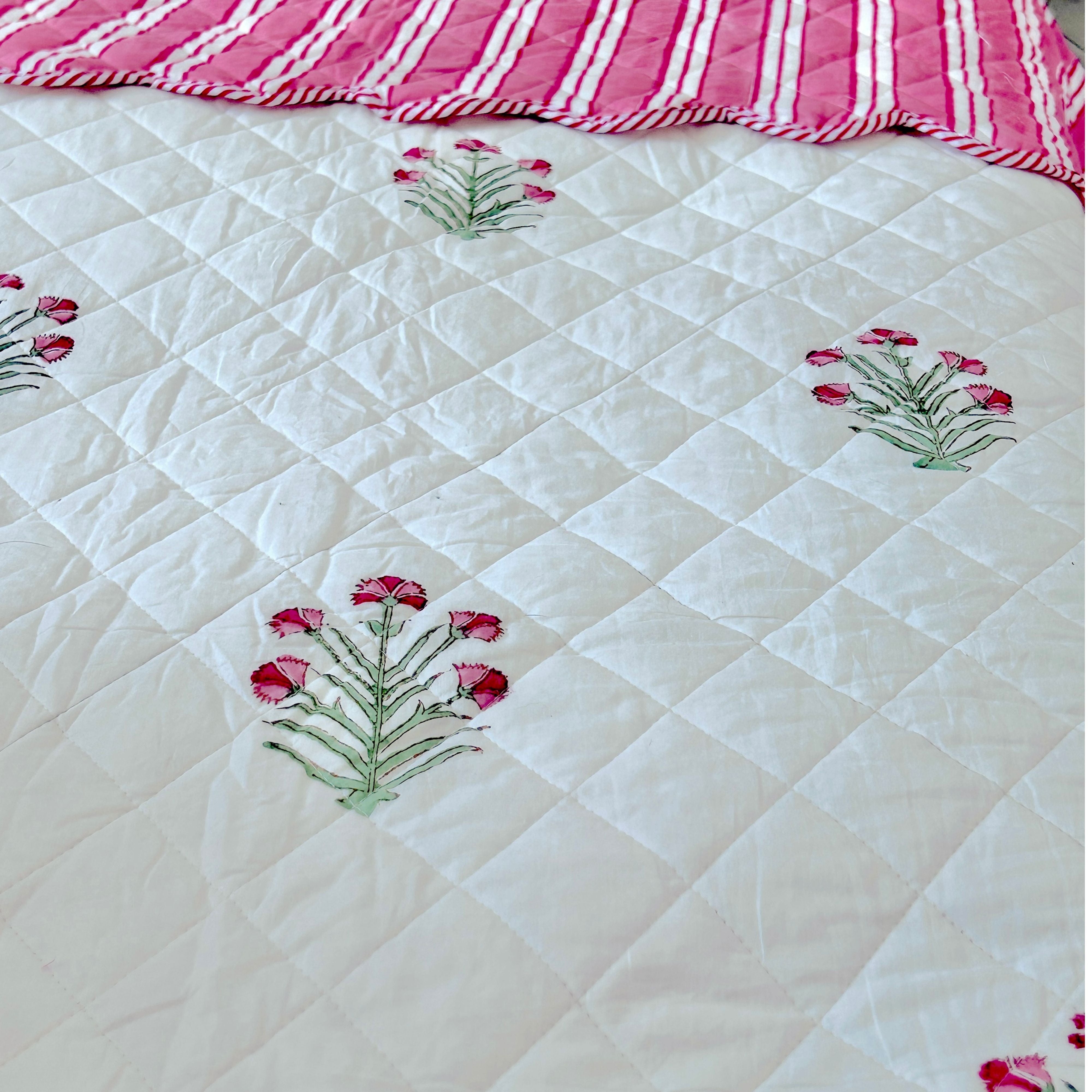 A close up of the super king bedpread dressed in pink and green flowers buta done with hand block printing, by The Charpoy