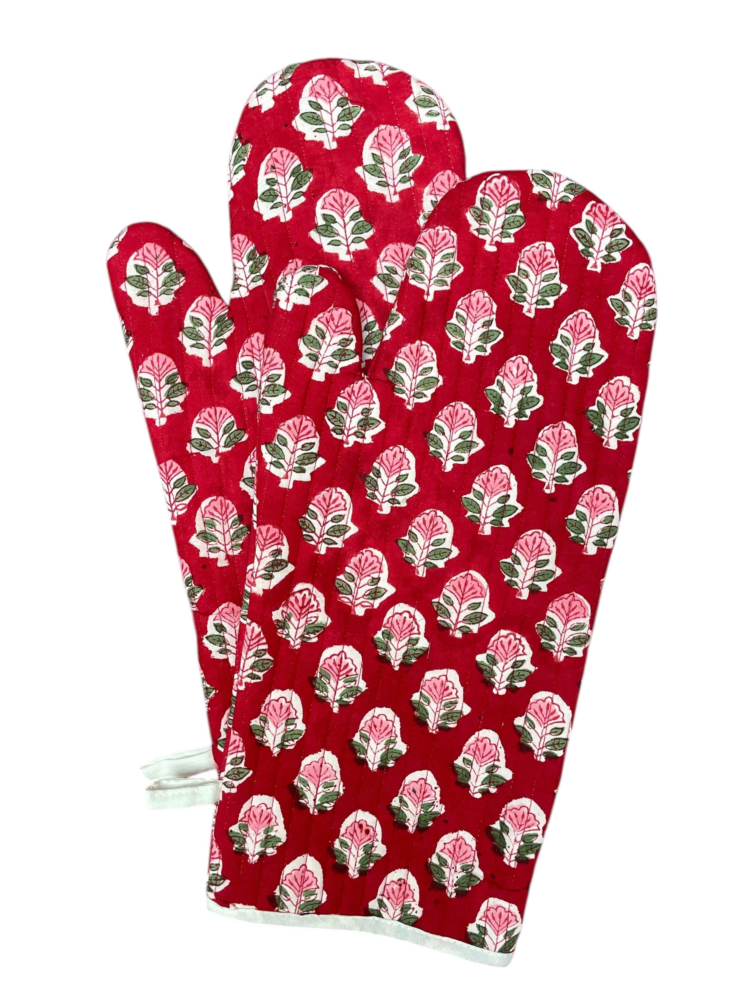 A pair of red oven gloves with a floral hand block print pattern.