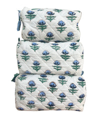 Set of three floral-patterned quilted  wash bags stacked on a wooden surface. The Charpoy 