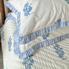 Jodhpur Blue Floral Hand Block Printed Quilt on a bed with matching ruffled pillows, artisanal made in Jaipur by The Charpoy