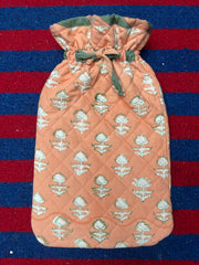 Hot water bottle cover in Quilted fabric with peach pattern on a red and blue striped background
