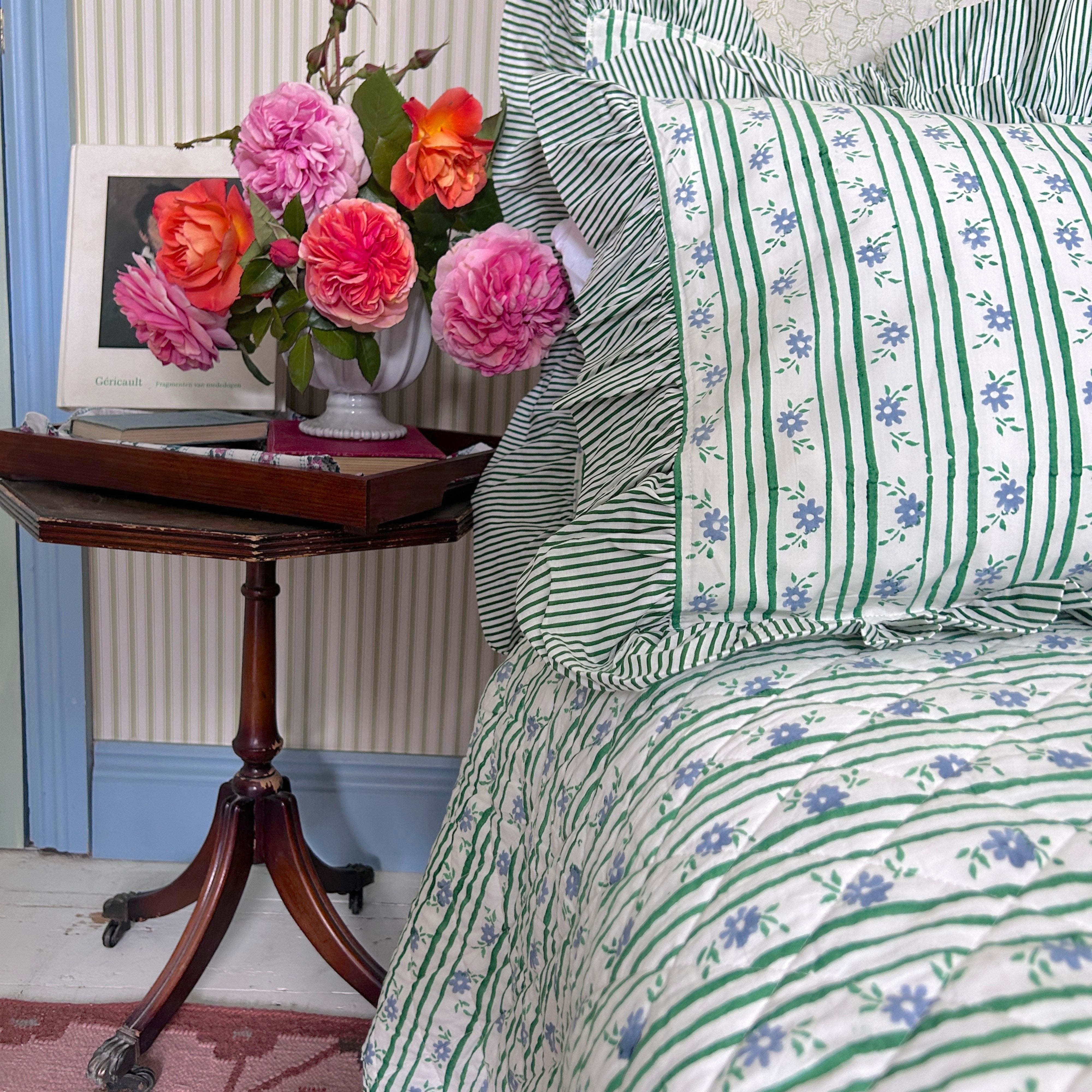 floral striped bedspread, side table with flowers. The Charpoy