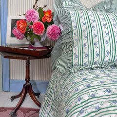 floral striped bedspread, side table with flowers. The Charpoy