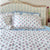 Floral patterned bedspread and pillows on a bed with striped headboard. The Charpoy