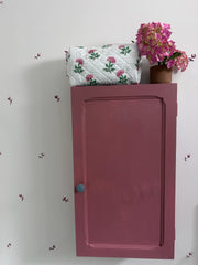 Pink And Green Flower Quilted Wash Bag hand block printed and lightly quilted by artisans in Jaipur by The Charpoy on a Pink cabinet and floral wall.