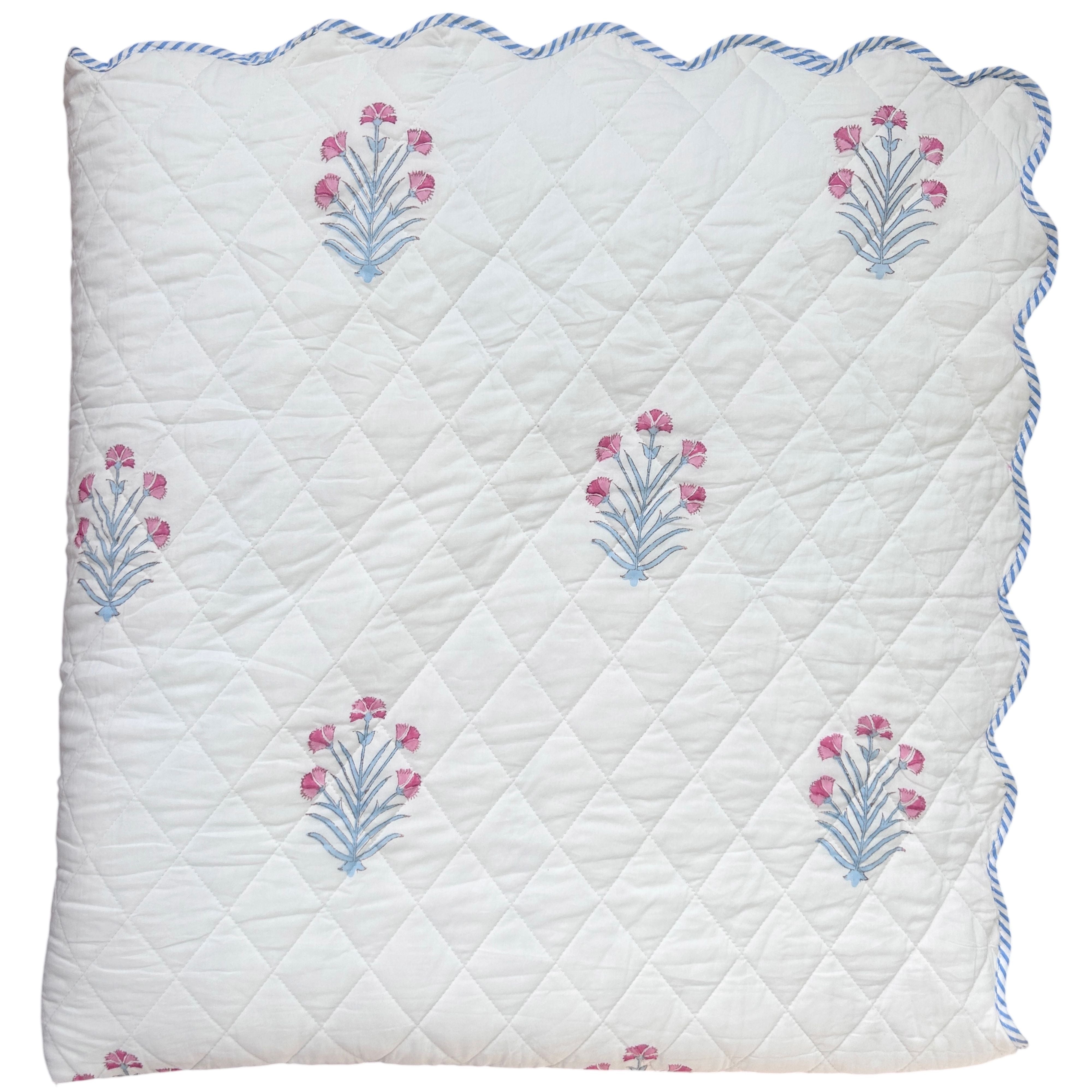 Quilted bedspread with floral hand block printed on a white background and scalloped edge The Charpoy