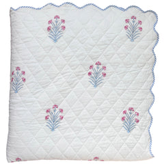 Quilted bedspread with floral hand block printed on a white background and scalloped edge The Charpoy