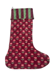 Red floral-patterned Christmas stocking with green trim on a white background