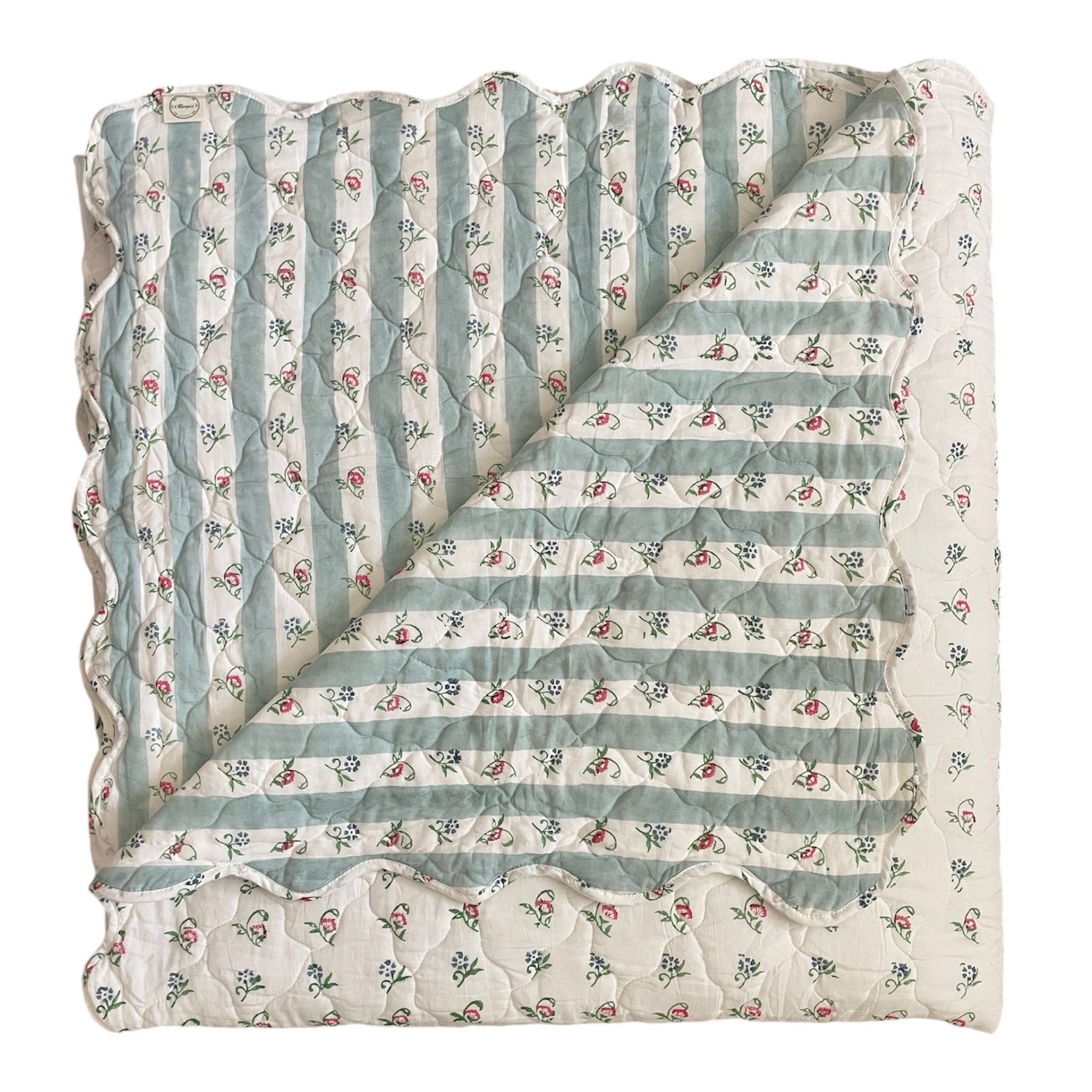 Quilted bedspread with a floral pattern in shades of blue and white, scalloped edges on the reverse. The Charpoy