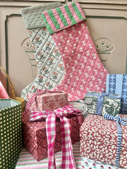 Decorative Christmas stockings and gift boxes with festive patterns on a wooden surface.