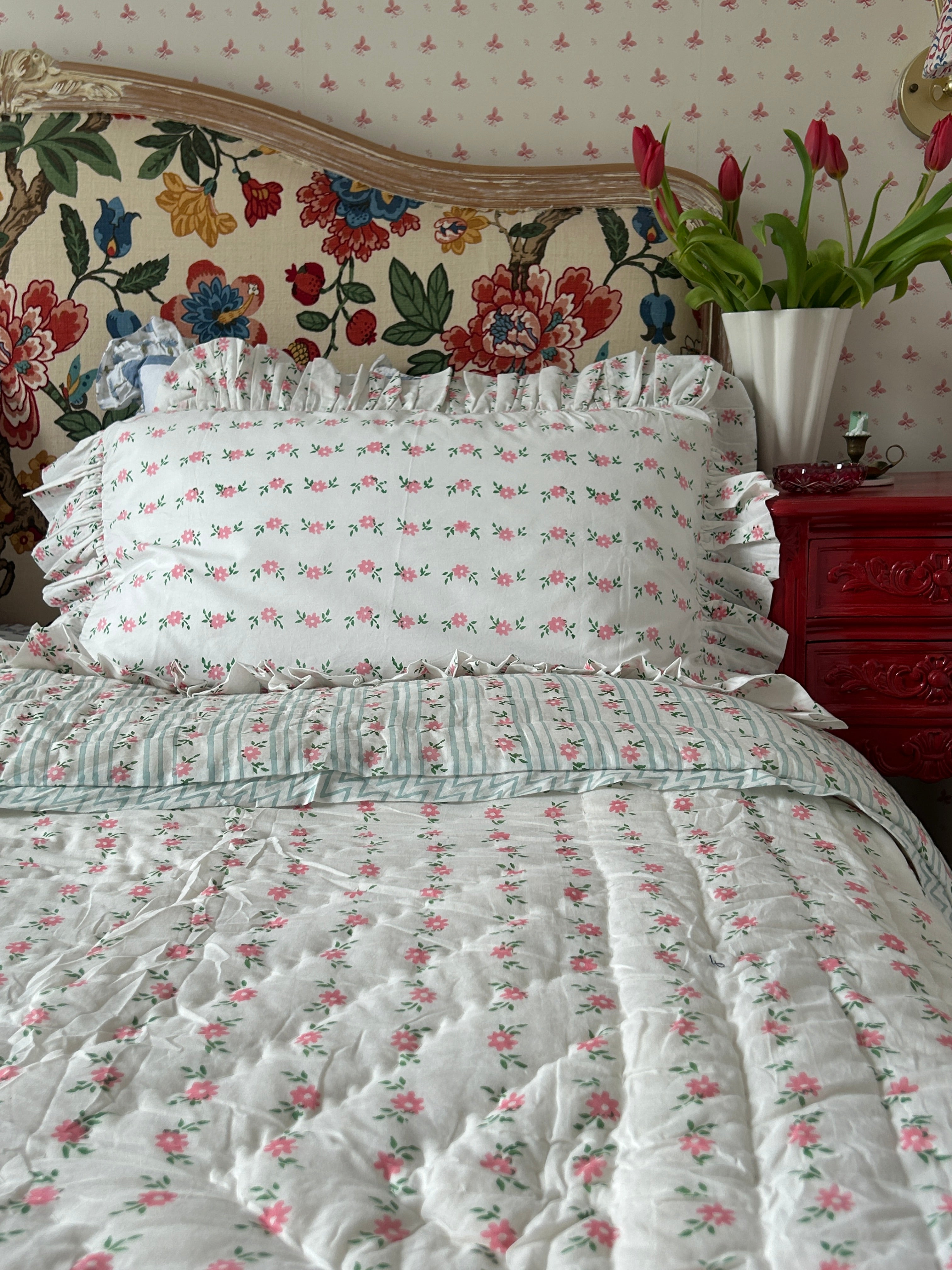 Floral bedspread and headboard with decorative elements on a bed.