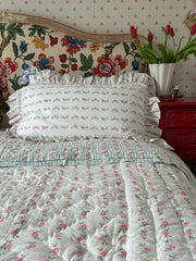 Floral bedspread and headboard with decorative elements on a bed.